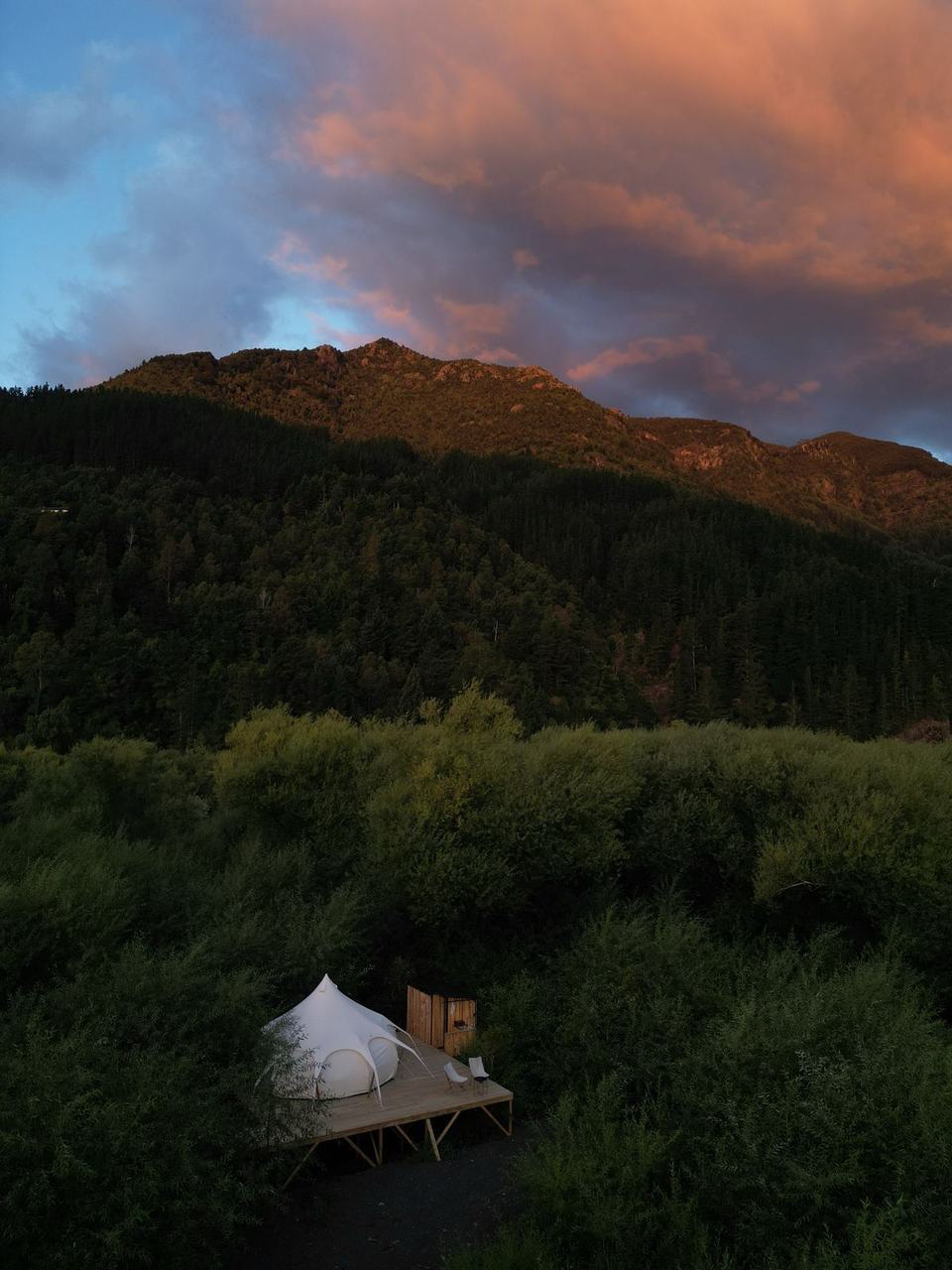 Atardecer sobre los cerros con una carpa entre los árboles